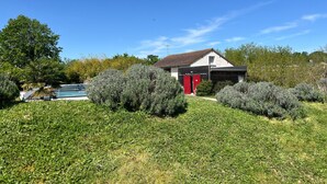 A house with a garage, surrounded by well-maintained bushes and a lawn. - Le Hameau du Peu - Happy Cottage with Shared Pool (Châteauvieux)