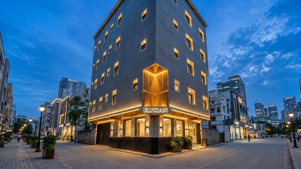 A modern hotel with a prominent entrance, multiple floors, and a cityscape in the background. - Hotel Elysian at Delhi Airport  (New Delhi)