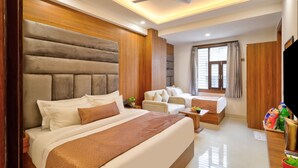 A hotel room with a large bed, a sofa, a desk, and a TV. - Hotel Elysian at Delhi Airport  (New Delhi)