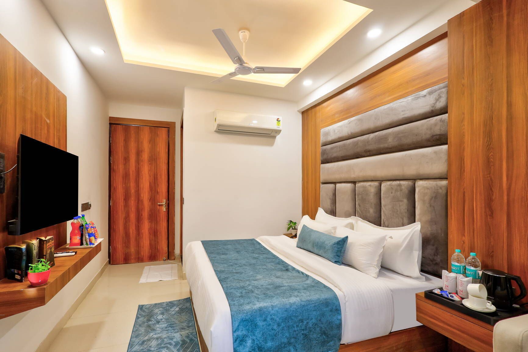 Un dormitorio moderno con cama, televisor, ventilador de techo y aire acondicionado.