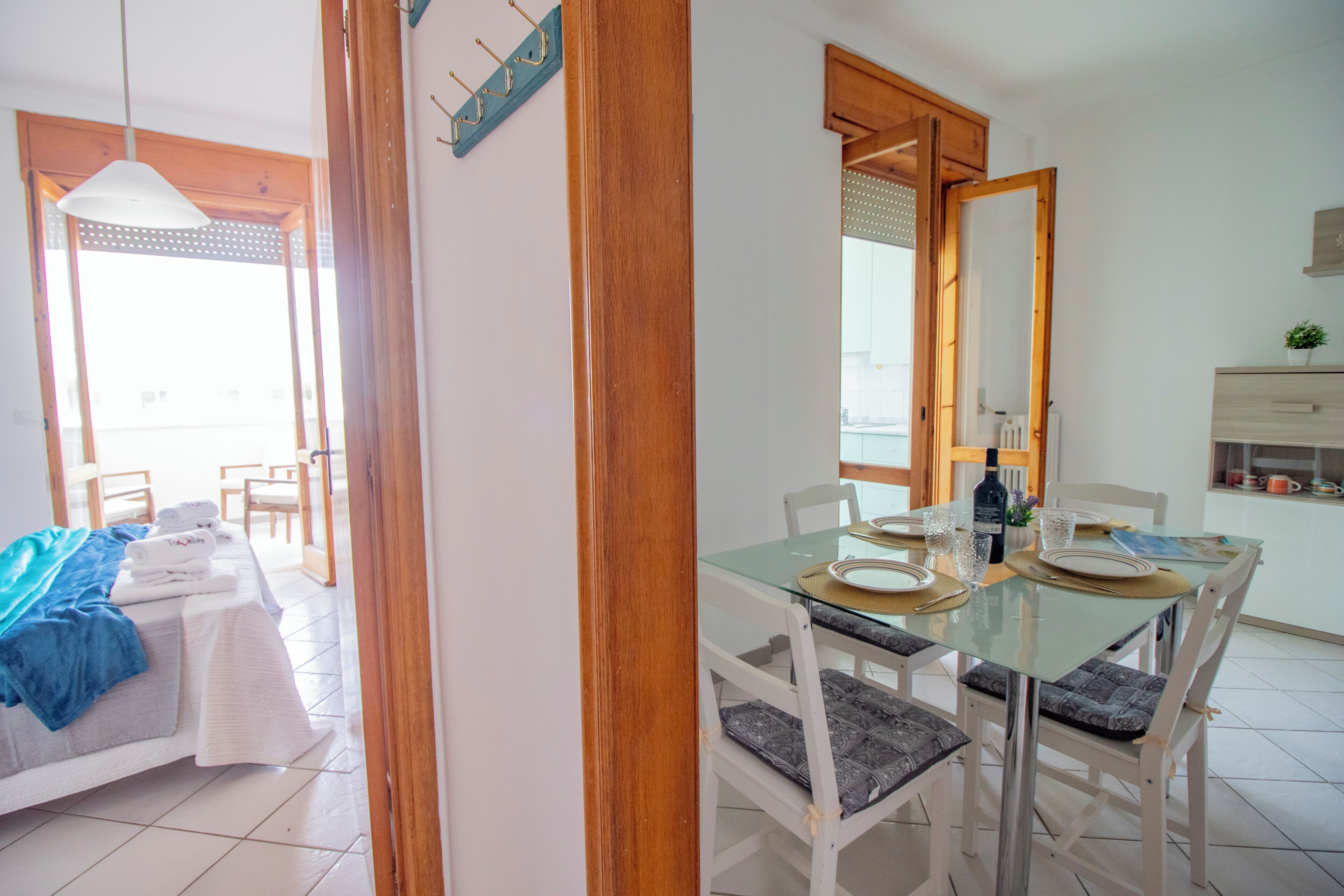 Un espace repas avec une table en verre, des chaises blanches et une vue sur l’extérieur.
