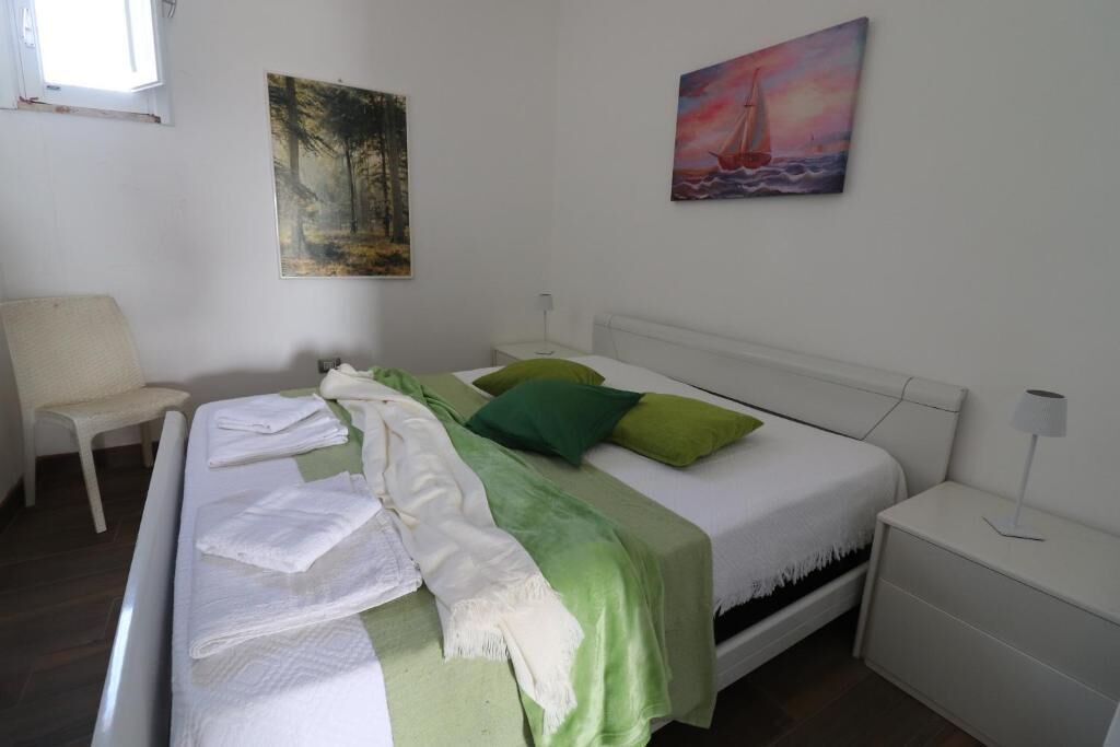 Ein Schlafzimmer mit einem Bett, einem Sessel, einem Nachttisch und zwei Bildern an der Wand.
