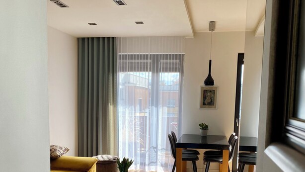 A modern living room with a yellow sofa, a glass coffee table, and a dining area with a black table and chairs. - OLIMPIC Apartament Suwałki AirCon Garage Self-Check In/Out (Suwałki)