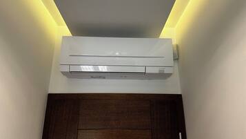 Un condizionatore d'aria bianco fissato a una parete, con una porta in legno sottostante.