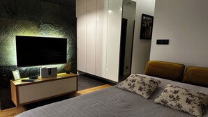 A bedroom with a bed, a TV, a wardrobe, and a mirror. - OLIMPIC Apartament Suwałki AirCon Garage Self-Check In/Out (Suwałki)
