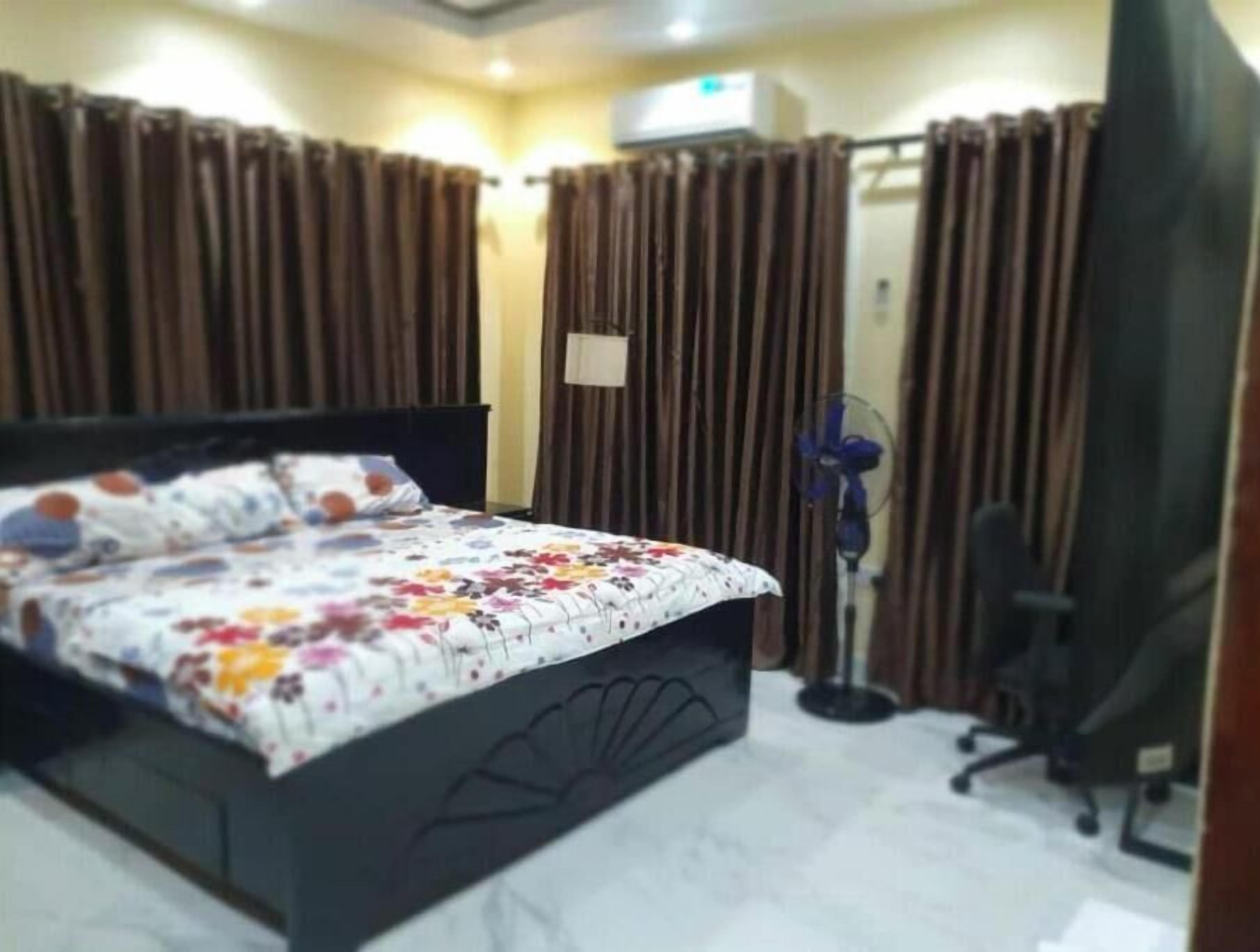 Quarto com cama, cortinas, escrivaninha e cadeira.