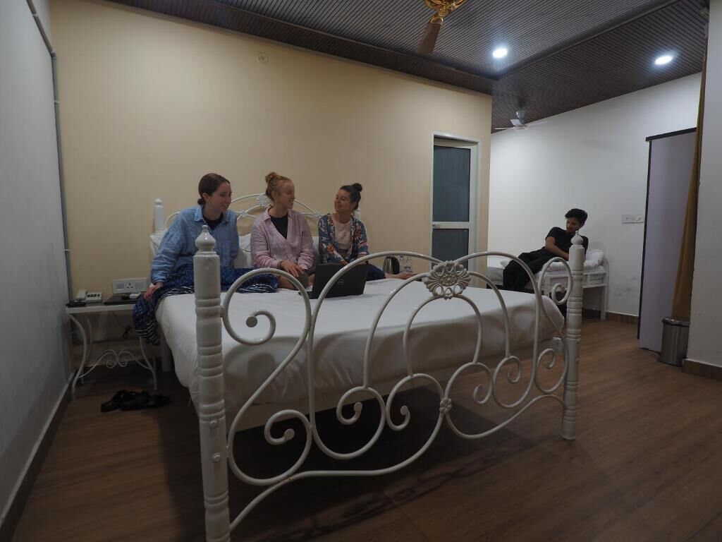 Um quarto com uma cama, mesa de cabeceira, janela e porta.