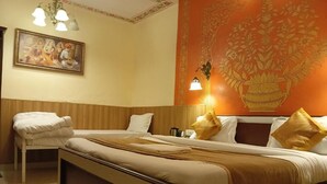 A hotel room with a bed, a chair, a painting, and a wall with a floral design. - Joey's hostel Jaipur (Jaipur)