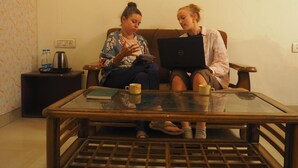 Two people sitting on a couch with a laptop and a glass table in front of them. - Joey's hostel Jaipur (Jaipur)