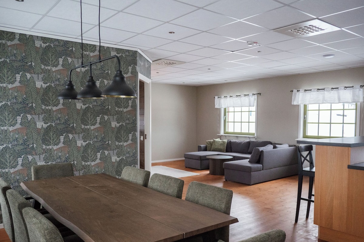 A modern interior with a dining area, a sofa set, and a kitchen counter.