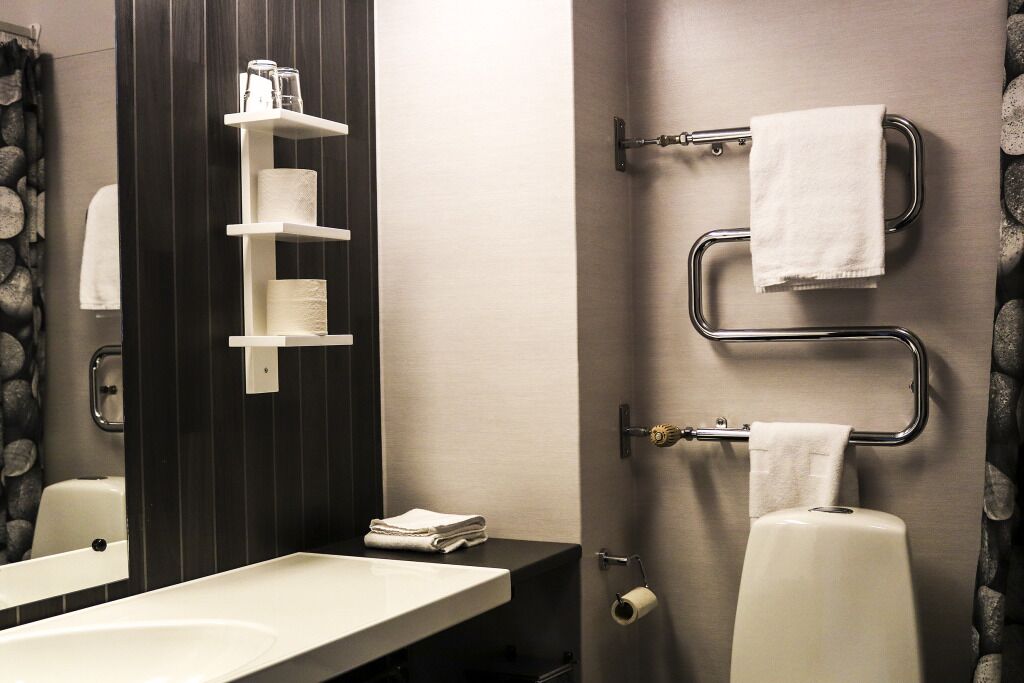 Un baño moderno con un lavamanos blanco, un espejo, un perchero para toallas y un soporte para papel higiénico.