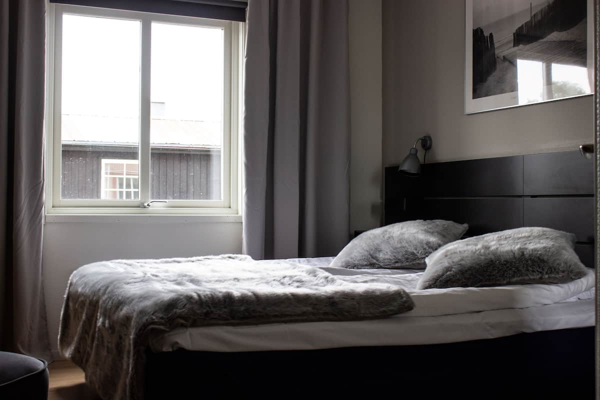 A bedroom with a bed, a window, and a wall-mounted picture.