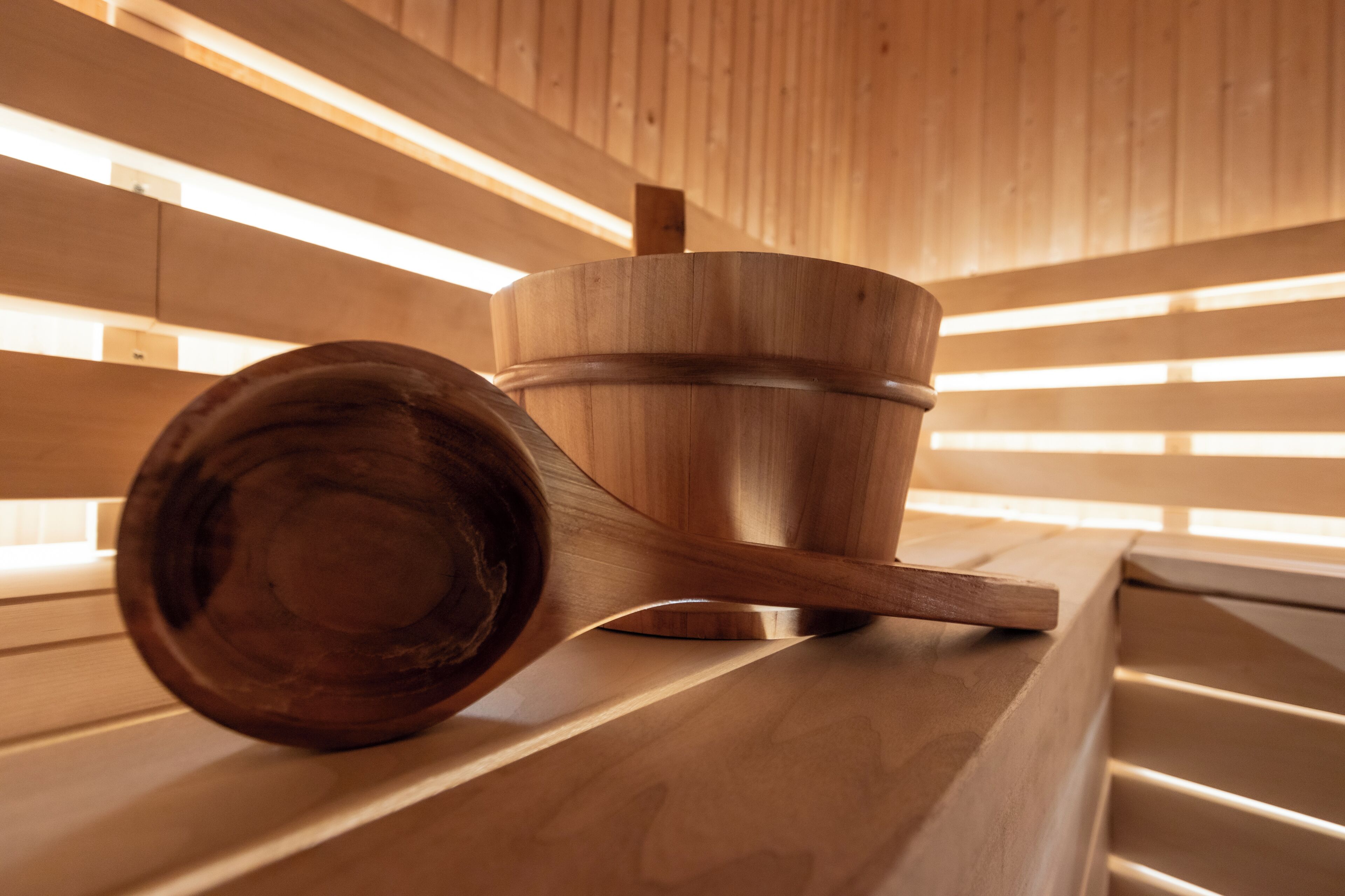Un sauna en bois, avec un grand seau en bois et un long banc en bois.
