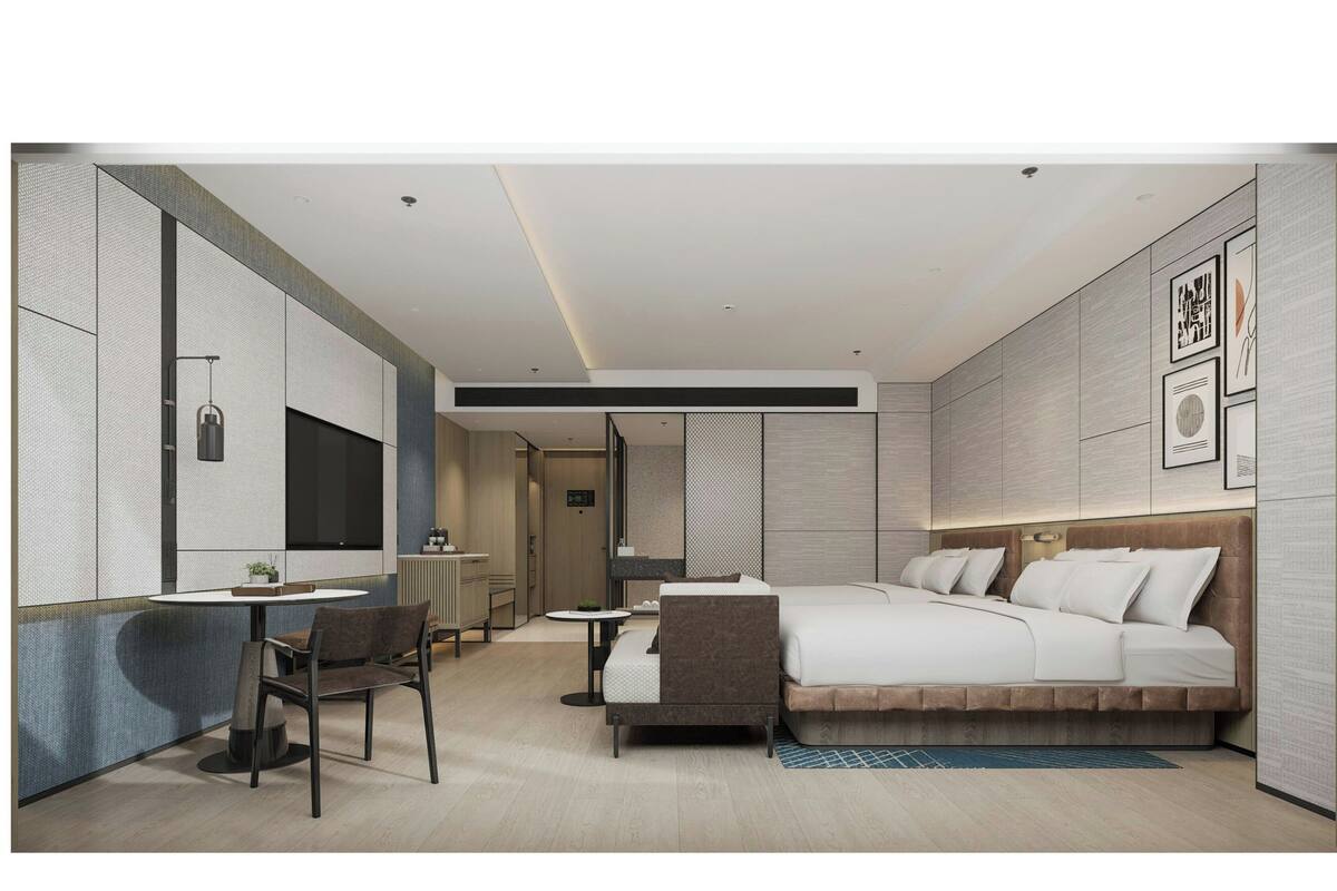 A modern hotel room with a bed, a desk, a chair, and a TV.
