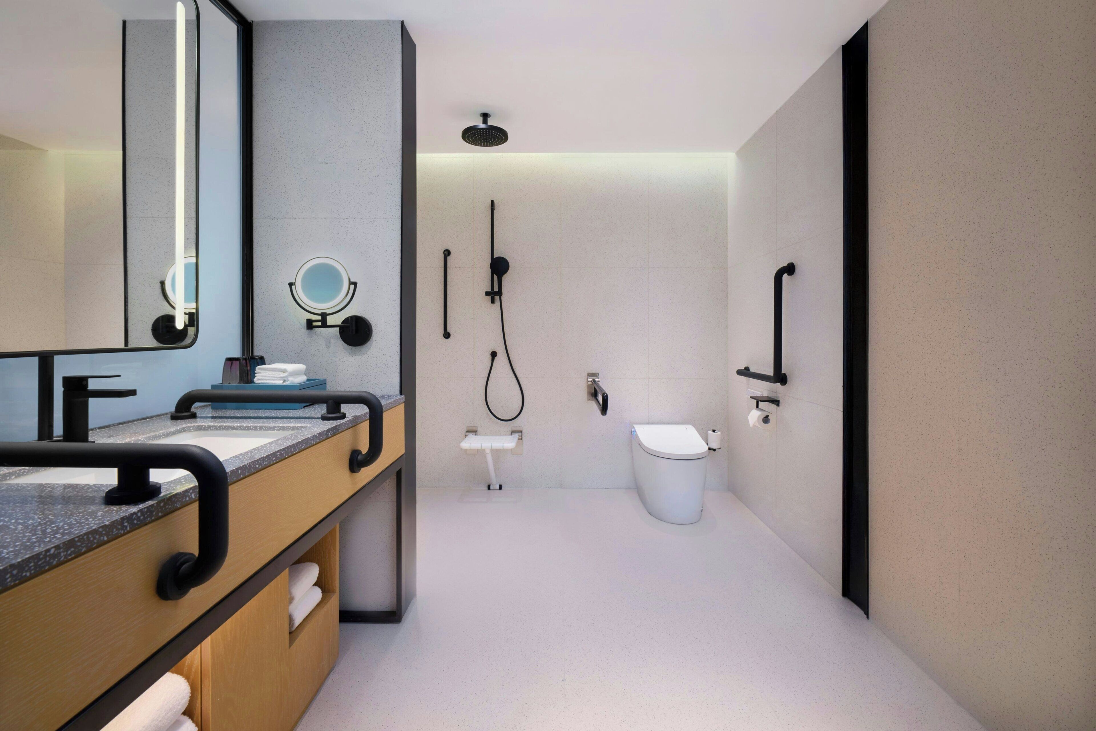 A modern bathroom with a vanity, mirror, towel rack, and a toilet.