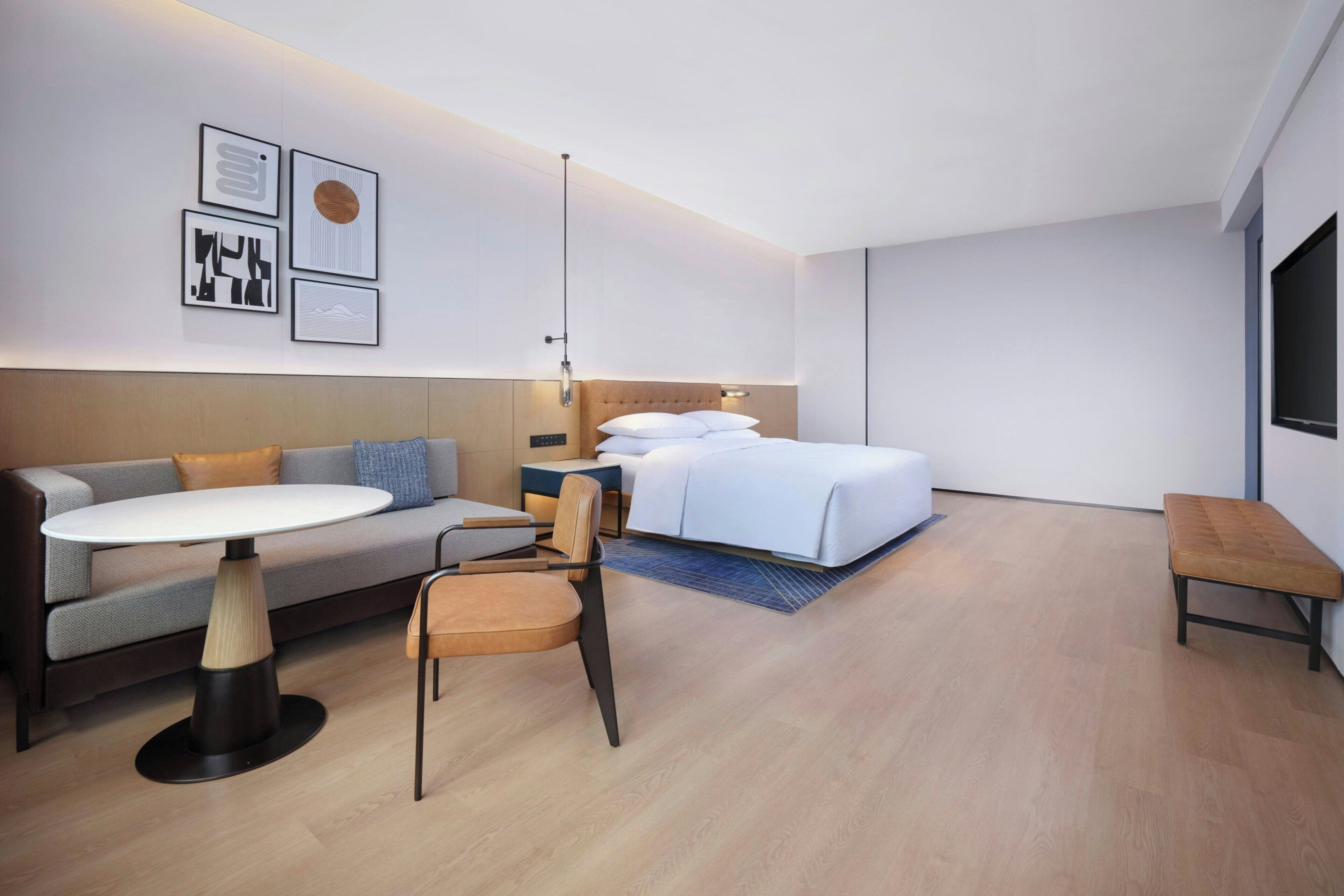 A modern hotel room with a bed, a sofa, a small table, and a chair.