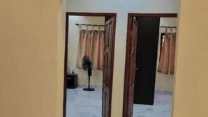 Un pasillo con suelo de mármol que conduce a una habitación con ventilador y cortinas.