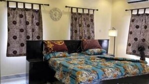 Un dormitorio con cama, cortinas, un reloj y un equipo de aire acondicionado.