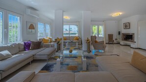 Amplia sala de estar con sofá modular, una mesa de centro de vidrio y una chimenea.