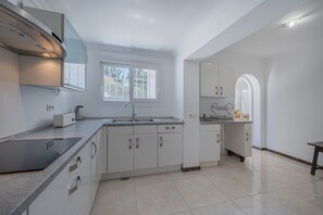 A modern kitchen with white cabinetry, a built-in stove, and a window providing natural light.