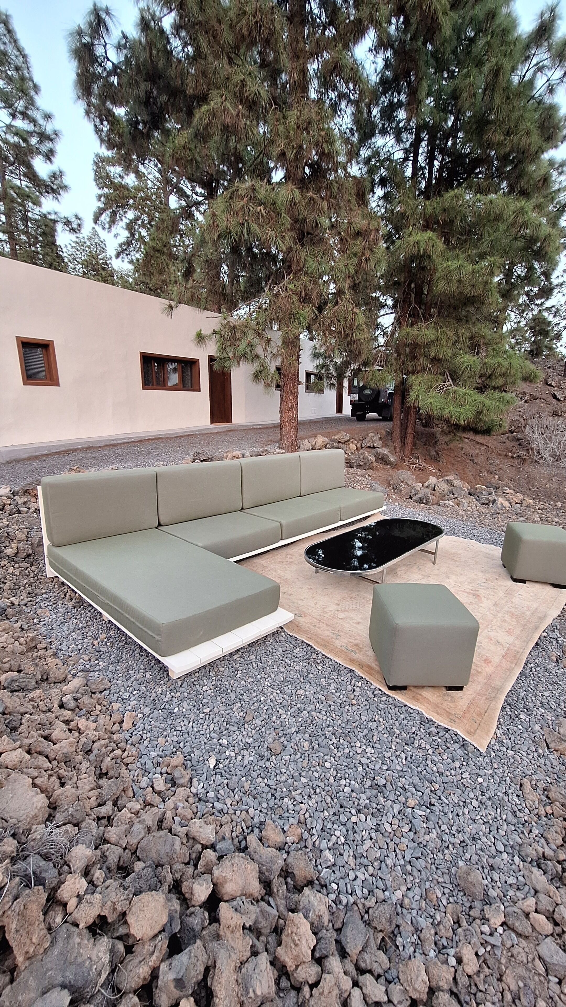 Un espace extérieur aménagé avec un canapé et des poufs, entouré de rochers et d’arbres.