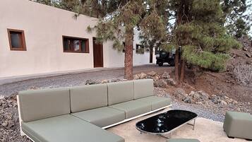 Un espace extérieur aménagé avec un canapé et des poufs, entouré de rochers et d’arbres.