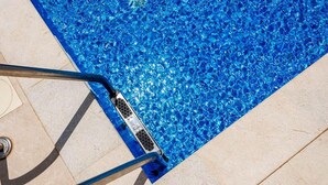 A swimming pool with clear blue water, a metal ladder, and a tiled floor. - Holiday Home Fulia with pool (Galižana)