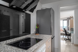 A modern kitchen with a granite countertop, a built-in stove, and a stainless steel refrigerator.