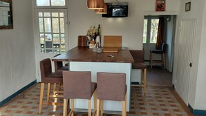 Ein Essbereich mit einem Holztisch, vier Stühlen, einem an der Wand befestigten Fernseher und einer zur Außenseite führenden Tür.