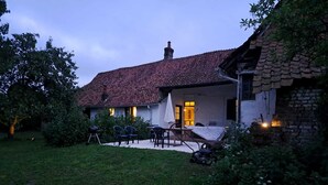 Ein Haus mit einem Ziegeldach, einer Terrasse mit Gartenmöbeln und einem Garten.