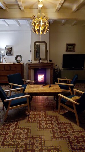 Un salon avec une cheminée, un téléviseur et un lustre.