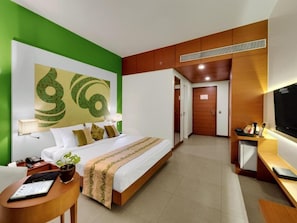 A hotel room with a bed, bedside table, lamp, and a TV.