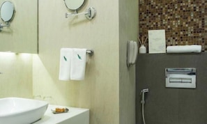 A bathroom with a large white sink, a mirror, a towel rack with two towels, a hairdryer, and a wall-mounted heater.