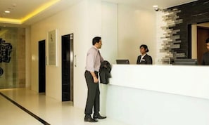 A reception area with a receptionist, a man waiting, and a modern interior design. - The Fern Residency (Mumbai)
