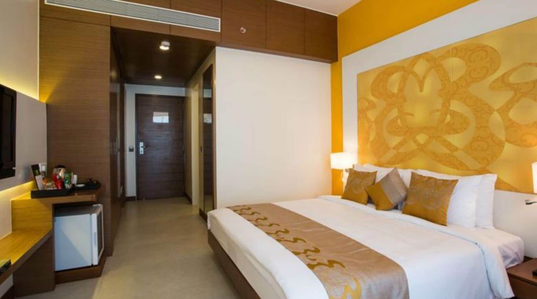 Ein Hotelzimmer mit einem Bett, Nachttischen, einem Schreibtisch und einer großen Wanddekoration.