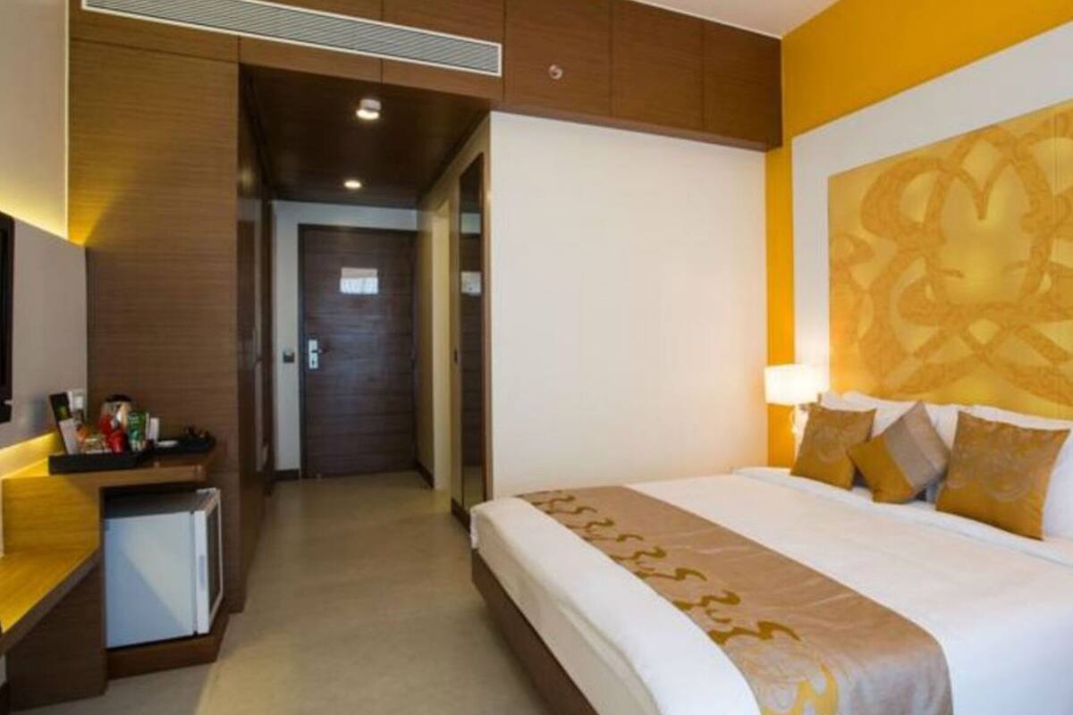 A hotel room with a bed, bedside tables, a desk, and a large decorative wall.