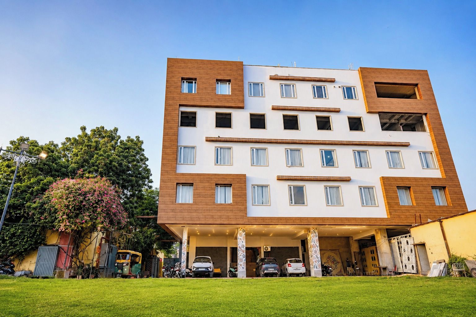 A multi-story building with a flat roof, a parking area in front, and a well-maintained lawn.