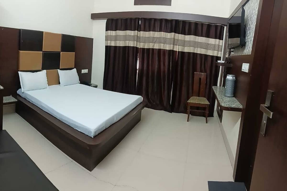 A hotel room with a bed, a desk, a chair, and a curtain.