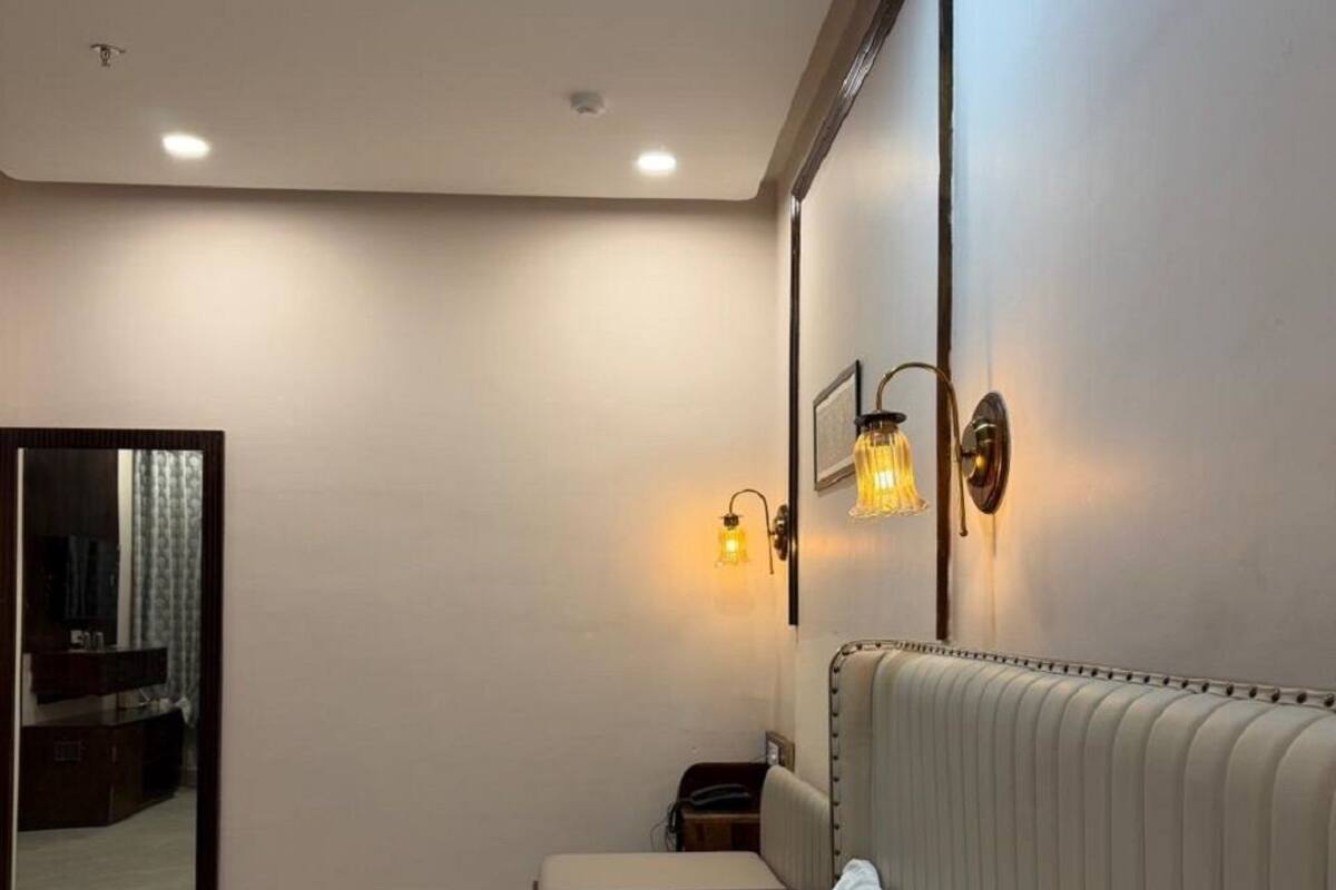 A hotel room with a bed, bedside table, lamp, and a mirror.