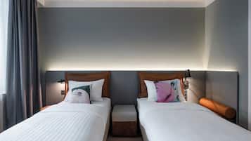 Una habitación de hotel con dos camas, una mesita y una mesita de noche con lámpara.