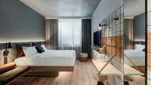 A modern hotel room with a bed, bedside table, TV, and a large mirror. - Moxy Budapest Downtown (Budapest)