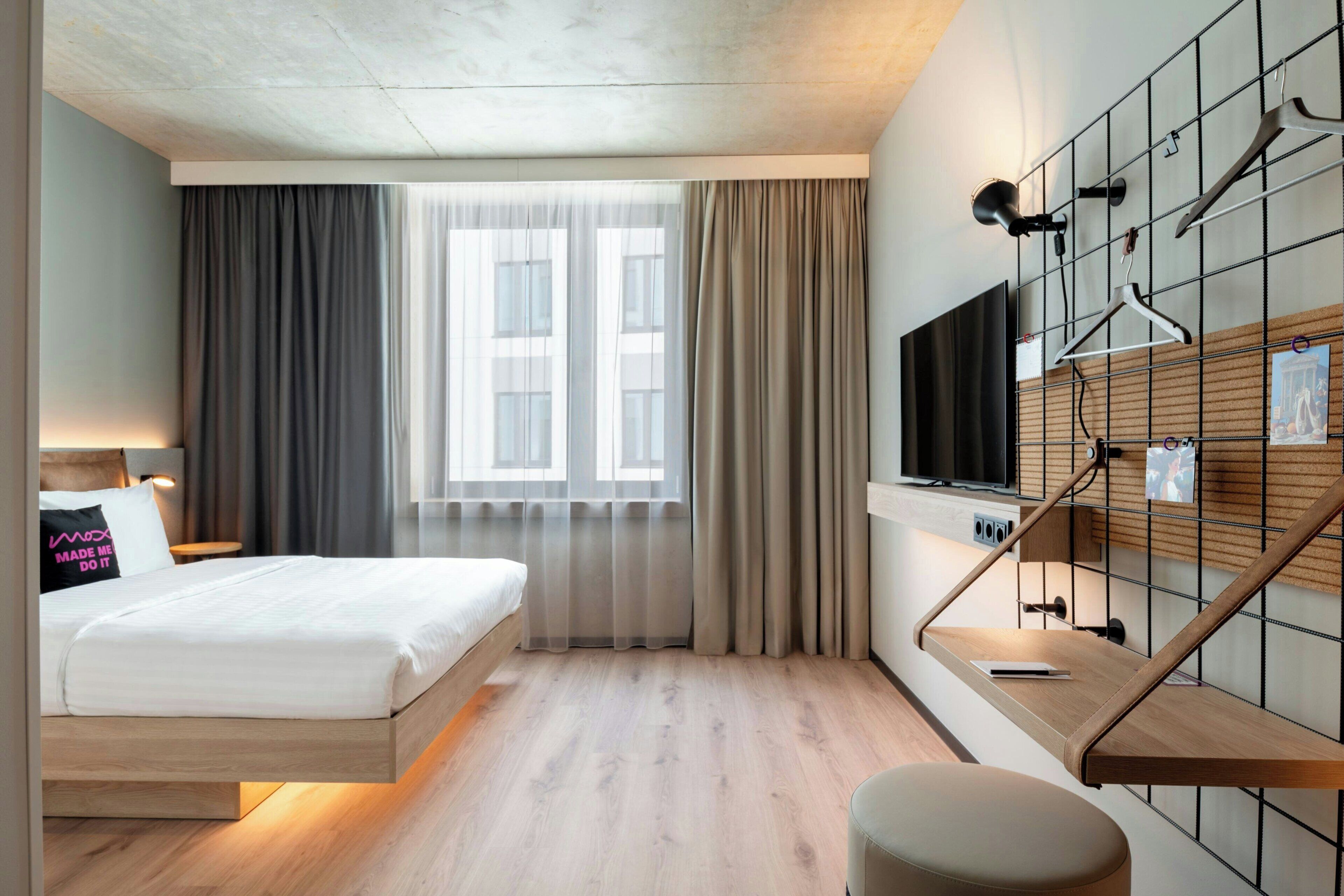 Una habitación de hotel moderna con cama, escritorio, televisor y vistas a la ciudad.