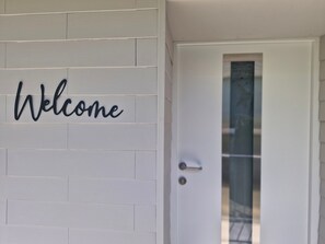 A white door with a 'Welcome' sign above it.