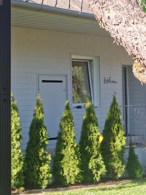 Un bâtiment blanc avec une pancarte indiquant « Bienvenue », une porte et une fenêtre.