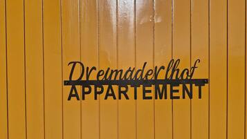 A yellow wall with the text 'Dreimädlerhof APARTMENT' in black.