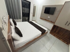 Ein Schlafzimmer mit Bett, Fernseher, Kleiderschrank und Spiegel.