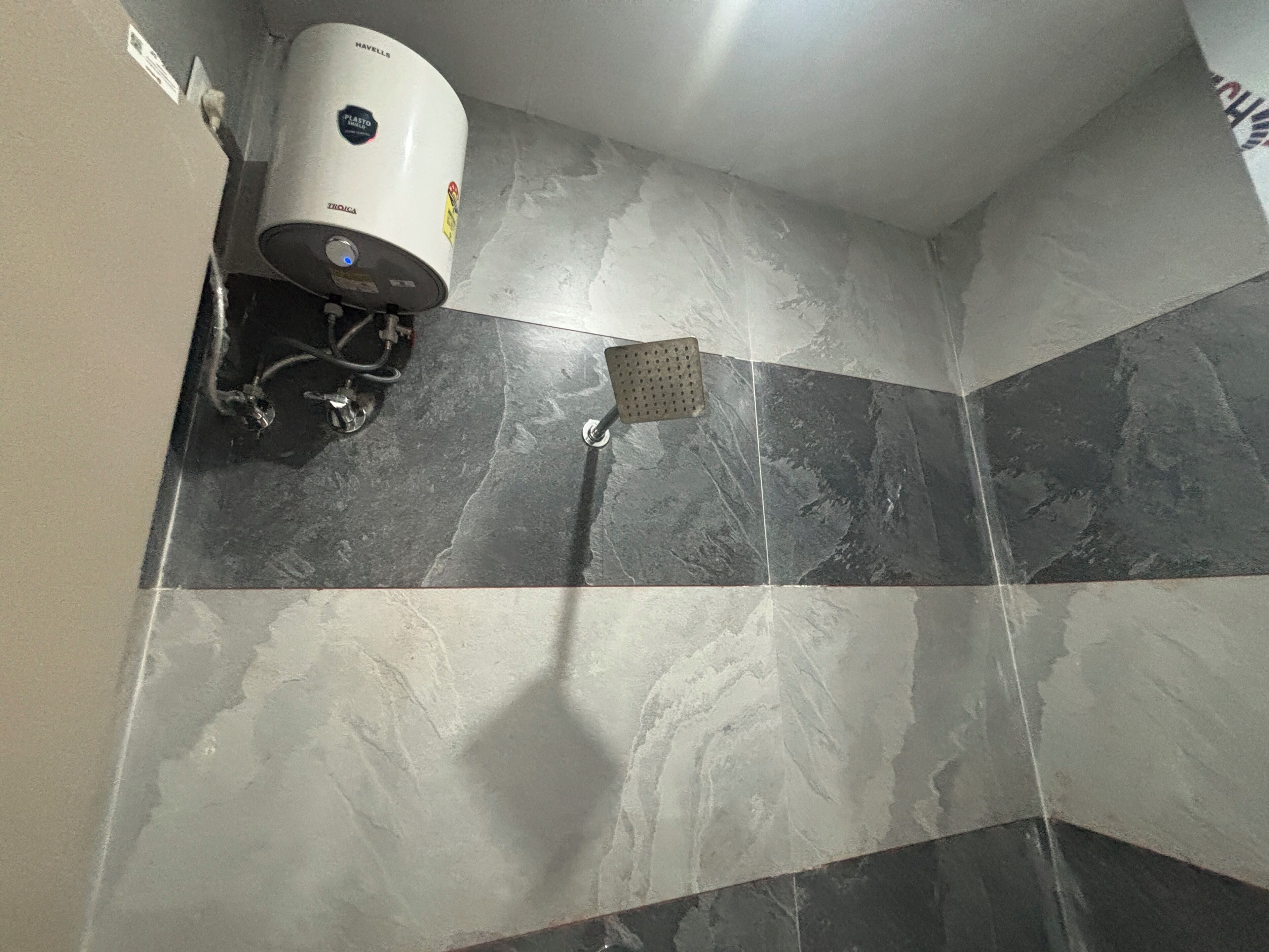 A bathroom with a shower, a water heater, and a tiled floor.