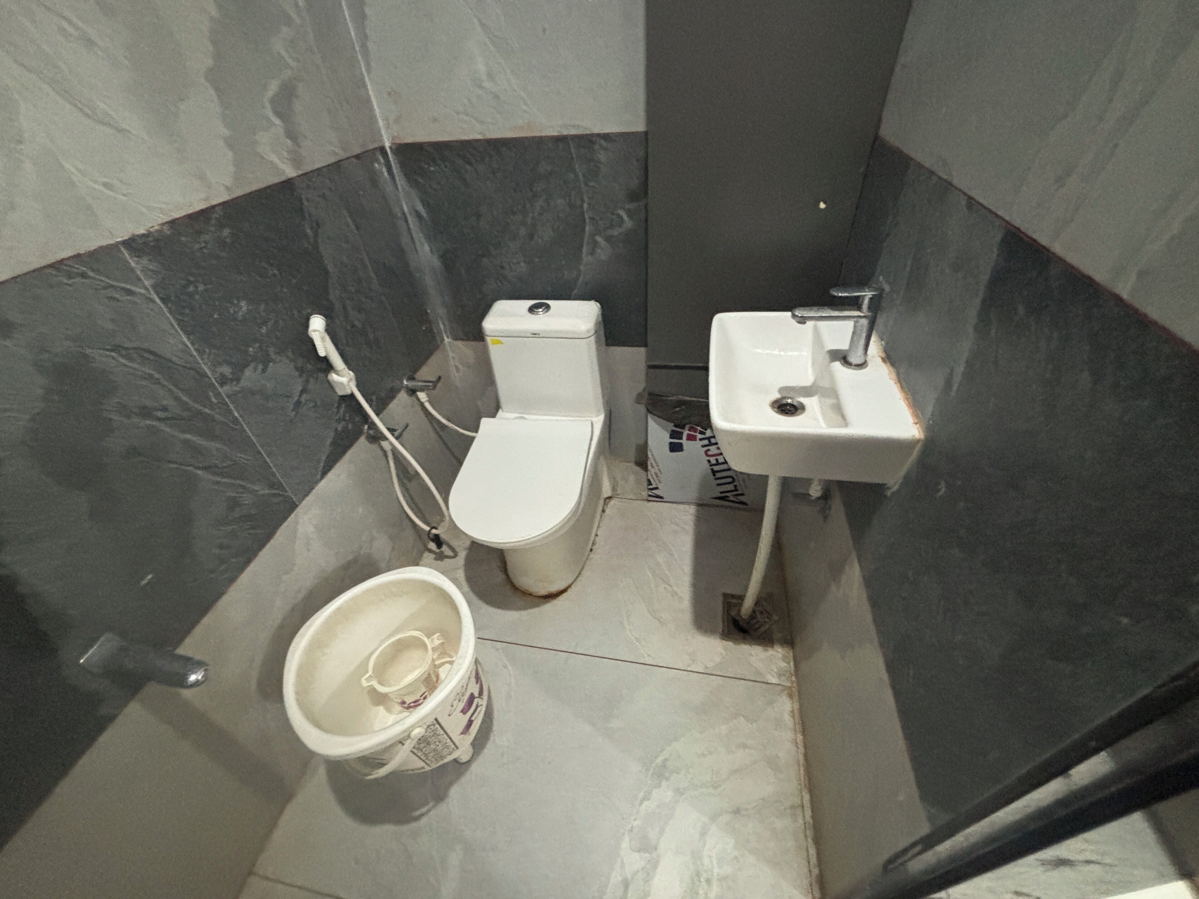 A small bathroom with a toilet, sink, and shower.