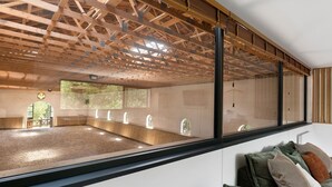 A room with a large window, a wooden ceiling, and a seating area with cushions. - Loft Cavalier – Domaine de Greffeil: Unique Stay Overlooking the Equestrian Arena (Greffeil)