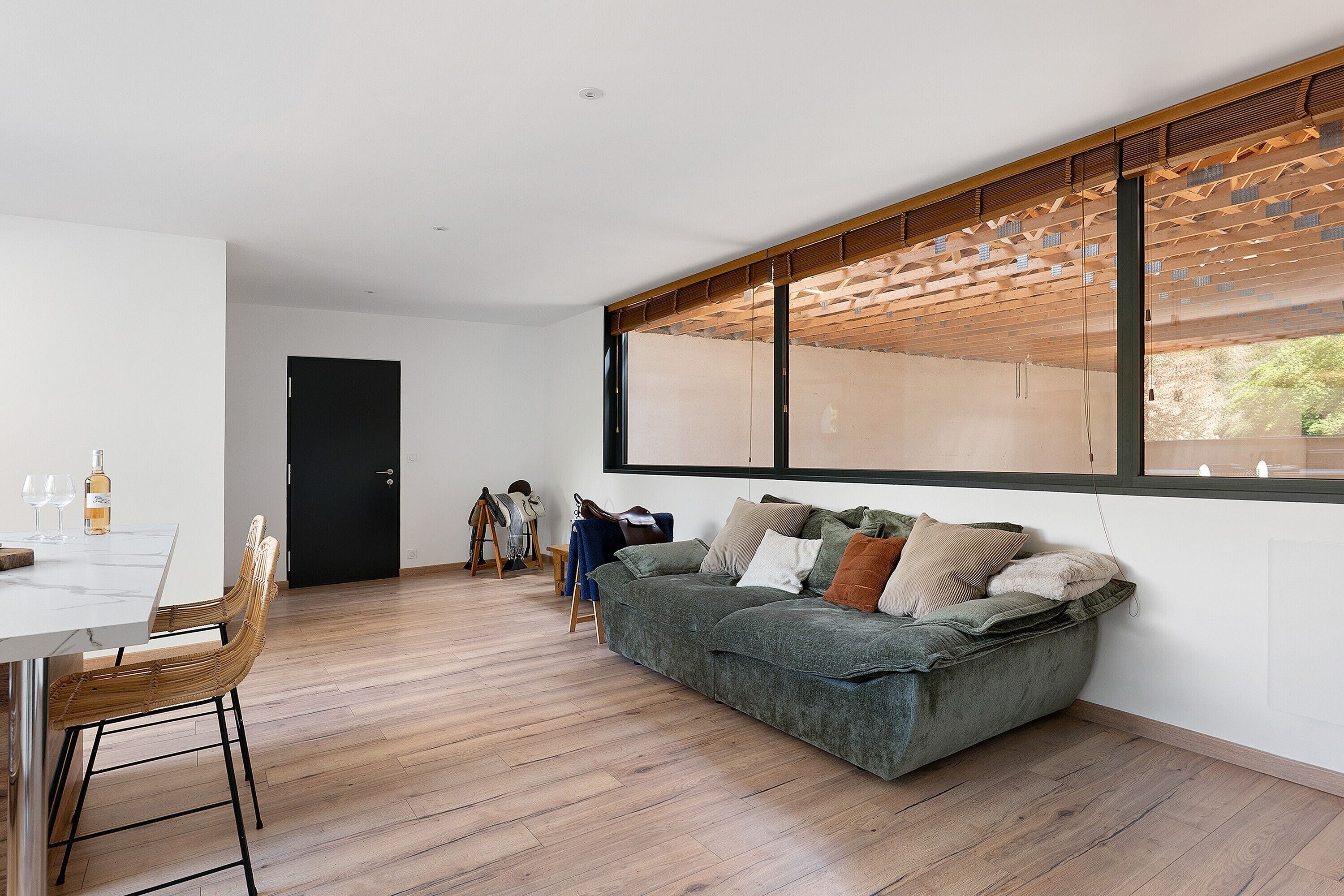 A modern living space with a dining area, a sofa, and a large window.